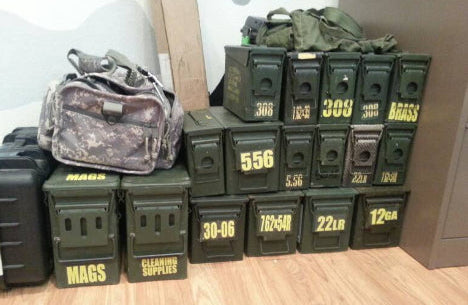 Stack of ammunition boxes and bags on a wooden floor